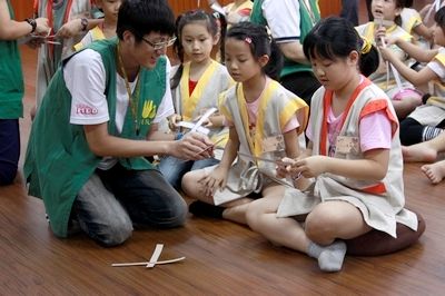 青年義工指導小朋友們完成環保玩具迴力鏢。